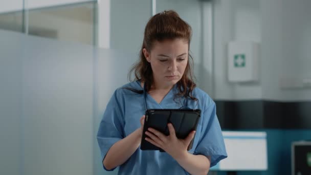 Nahaufnahme eines Arzthelfers, der auf den Tablet-Bildschirm mit Informationen blickt — Stockvideo