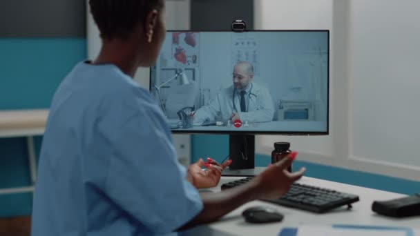 Infirmière afro-américaine utilisant appel vidéo pour la conversation avec le médecin — Video