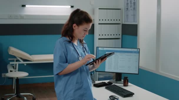 Asistente médico mirando la pantalla de la tableta para obtener información — Vídeos de Stock