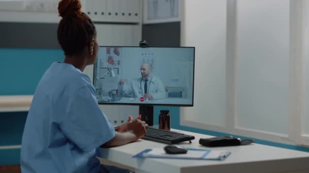 Kadın hemşire doktorla görüntülü konuşma için bilgisayar kullanıyor. — Stok video