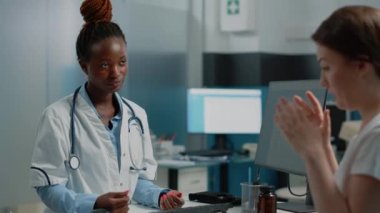 Afrikalı Amerikalı sıhhiyeci beyaz bir hastayla hastalıklar hakkında konuşuyor.