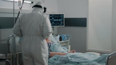 Koronavirüslü hasta koruyucu kıyafetli doktorla konuşuyor.
