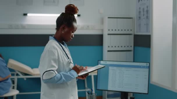 Черный врач смотрит на цифровой планшет для назначения — стоковое видео