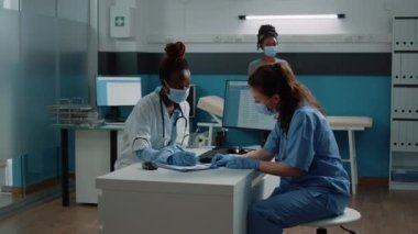 Doktor ve hemşireden oluşan çok ırklı bir ekip sağlık kontrolü belgesi hazırlıyor.