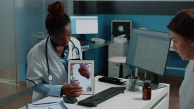 Afro-Amerikan doktor tablette kardiyovasküler görüntü gösteriyor.