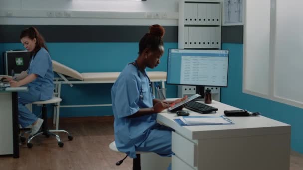 Afrikaans-Amerikaanse verpleegkundige met behulp van digitale tablet voor behandeling — Stockvideo