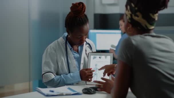 Africký americký lékař a pacient při pohledu na lidskou kostru — Stock video