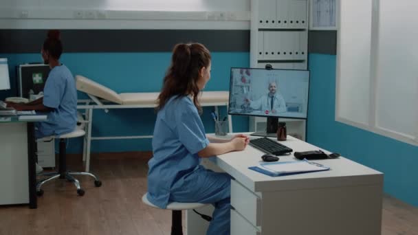Медсестра разговаривает с врачом на видео-звонок за профессиональным советом — стоковое видео
