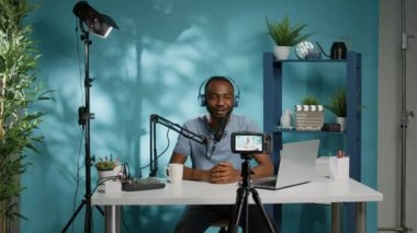 Podcast kaydederken kameraya el sallayan neşeli vlogger
