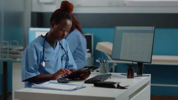 Infirmière afro-américaine tenant tablette numérique pour la visite de contrôle — Video