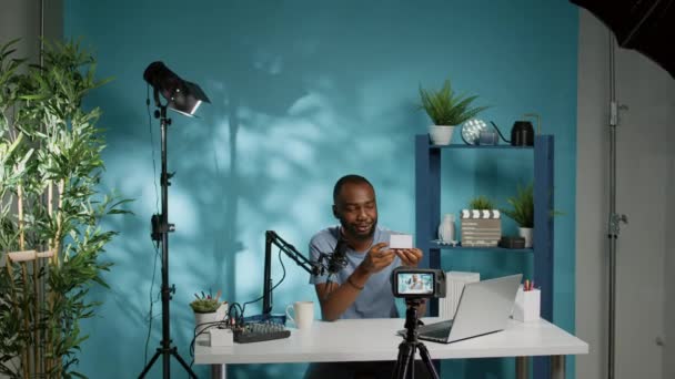 Mann zeigt Produkt vor Kamera und filmt Vlog — Stockvideo