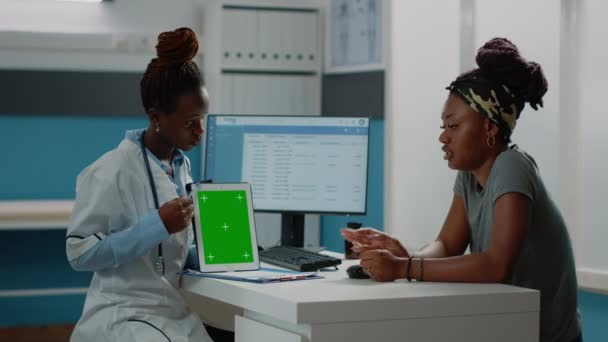 Sıhhiye yeşil ekranlı tableti işaret ediyor ve hastayla konuşuyor — Stok video