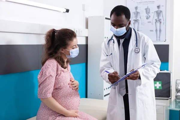 Especialista mostrando documentos de check-up para paciente grávida — Fotografia de Stock