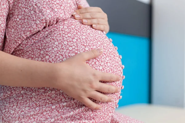 Blisko kobiety w ciąży trzymającej się za ręce na brzuszku — Zdjęcie stockowe