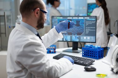 Biyolog araştırmacı elinde kan örneği tutuyor. DNA örneğini analiz ediyor.
