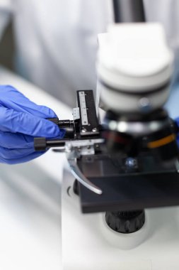 Biyolog kadının eli yakın plan. Kan örneğine şeffaf cam koyuyor.