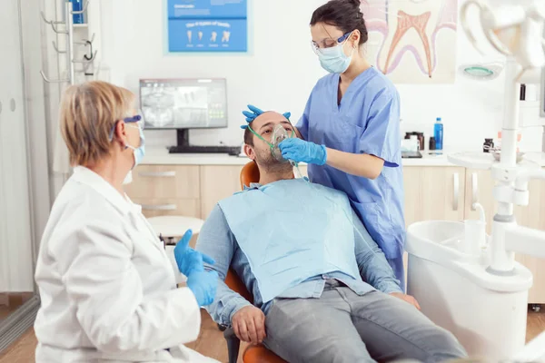 Медсестра-стоматолог надевает маску оксигена перед операцией на зуб — стоковое фото