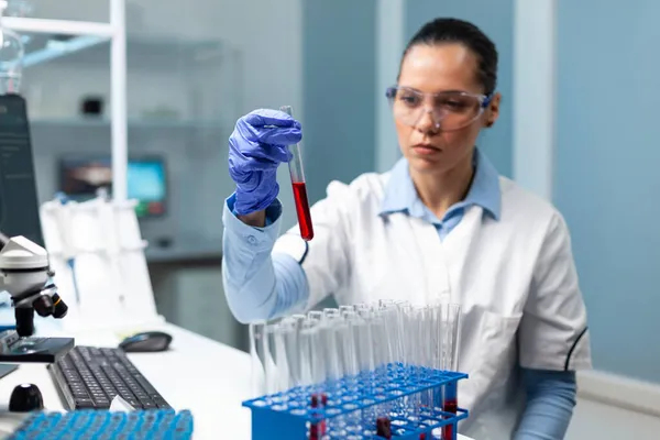 Científico médico mirando el tubo de análisis de sangre trabajando en el experimento de bioquímica —  Fotos de Stock