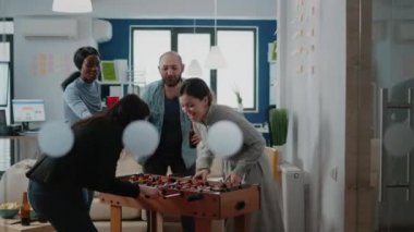 Neşeli iş arkadaşları langırt masasında futbol oynuyorlar.