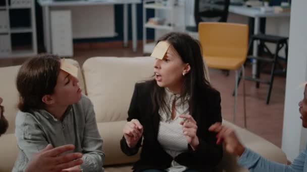 Close up of workmates enjoying game to guess with sticky notes — Stock Video