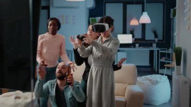 İş arkadaşları tezahürat yaparken joystick ve vr gözlük kullanan bir kadın