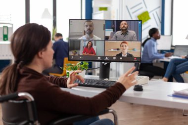 Tekerlekli sandalyedeki felçli iş kadını çevrimiçi video görüşmesi yapıyor.