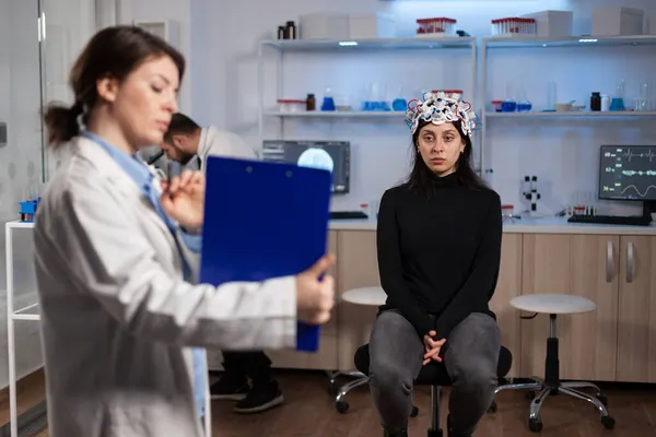 Femme patiente portant un scanner cérébral debout sur une chaise dans un laboratoire de neurologie — Photo