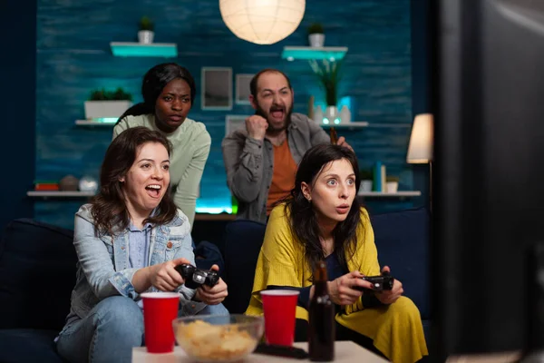 Захоплені жінки друзі сидять на дивані, виграючи відеоігри, використовуючи ігровий джойстик — стокове фото