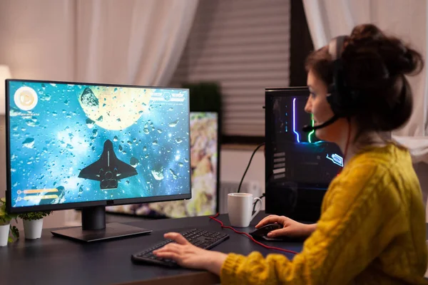 Фокусована жінка-гравець з навушниками, що грають у відеоігри космічного шутера — стокове фото