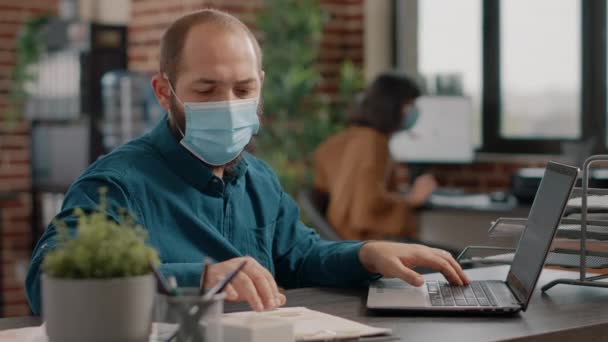 Ondernemer vergelijkt informatie op papier en laptop — Stockvideo