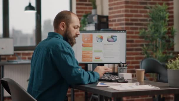 Zaměstnanec pracující s datovými grafy sazeb v počítači na stole — Stock video