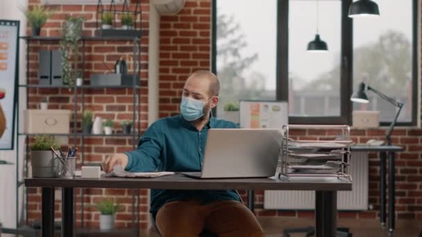 Hombre de negocios con máscara facial y mirando documentos — Vídeo de stock