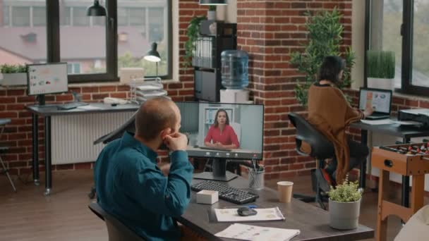 Empreendedor usando fones de ouvido para falar com o gerente em videochamada — Vídeo de Stock
