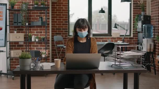Πορτρέτο της γυναίκας με μάσκα προσώπου που εργάζονται σε φορητό υπολογιστή — Αρχείο Βίντεο