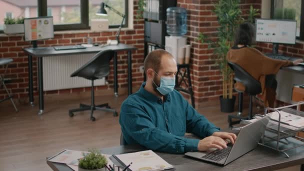 Retrato de homem de negócios com máscara facial trabalhando com laptop — Vídeo de Stock