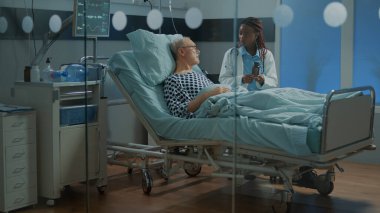 Klinikteki sıhhiye, hastane koğuşundaki yaşlı hastalara ilaç veriyor.