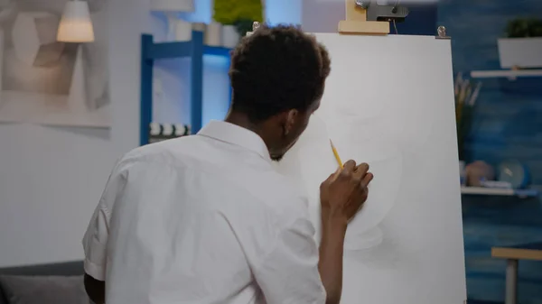 Μαύρος νεαρός καλλιτέχνης ρετουσάρισμα σχεδιασμό αγγείων σε καμβά και καβαλέτο — Φωτογραφία Αρχείου