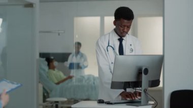 Doktor olarak çalışan adam bilgisayar ve belge kullanıyor.