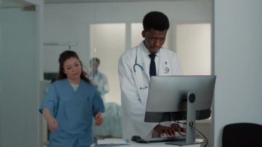 Bilgisayar ve klavyeyle çalışan Afrikalı Amerikalı doktor.