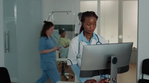 Vrouw werkzaam als arts met stethoscoop met behulp van computer — Stockvideo