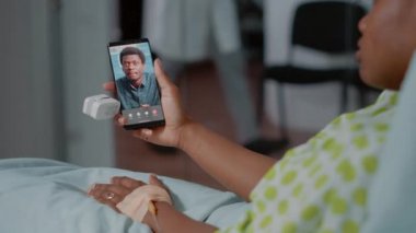 Video bağlantısı olan akıllı telefon kullanan Afrikalı Amerikalı bir kadın.