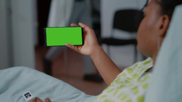 Chory pacjent trzymający smartfona z poziomym zielonym ekranem — Wideo stockowe