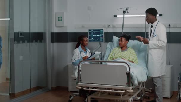 Zespół medyczny rozmawia z chorą kobietą na oddziale szpitalnym — Wideo stockowe