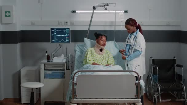 Doctor toont röntgenscan op tablet aan gewonde patiënt — Stockvideo
