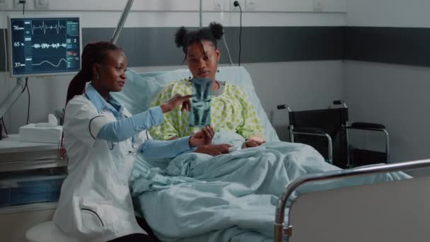 Médico mostrando resultados de radiografia para mulher doente na cama — Vídeo de Stock
