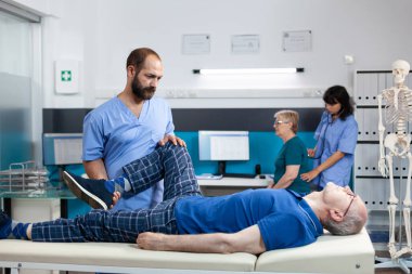 Ortopedi hemşiresi dizinden yaralanan hastaya yardım ediyor.