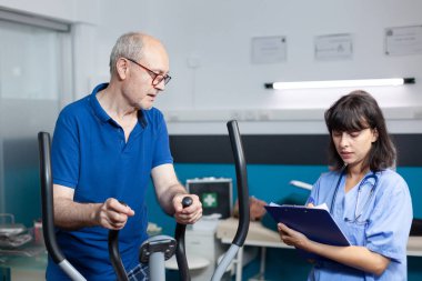 Hemşire fiziksel iyileşme sürecinde yaşlı adama yardım ediyor.