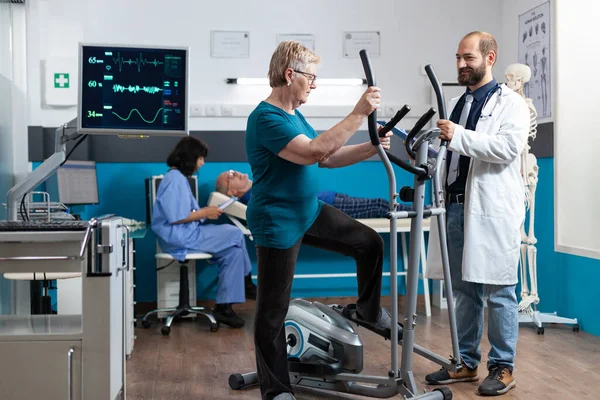 Femme âgée utilisant un vélo électrique pour l'exercice physique — Photo