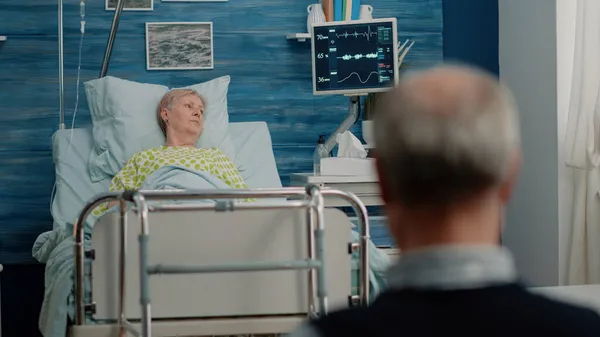 Kvinna med sjukdom vilar i sjukhussäng med IV droppåse — Stockfoto