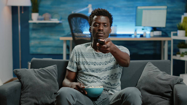 POV of adult switching channels with TV remote control